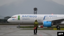 Một nhân viên mặt đất hướng dẫn cho máy bay của Bamboo Airways trên đường băng ở sân bay quốc tế Nội Bài, Hà Nội, trong ngày hoạt động đầu tiên của hãng hôm 16/1/2019.