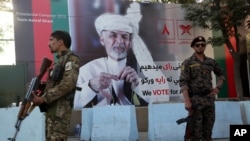 Afghan security forces stand guard in front of an election poster for presidential candidate Ashraf Ghani in Kabul, Afghanistan, Sept. 23, 2019. 