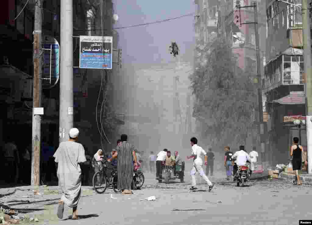 Residents run as smoke and dust rise after a jet shelled a street in al-Shaar, Aleppo, Syria, September 16, 2012.