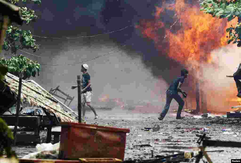 Những người đ&agrave;n &ocirc;ng Rohingya đứng giữa những ng&ocirc;i nh&agrave; bị đốt ch&aacute;y tại Sittwe, 10/6/2012.