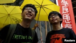 Joshua Wong (phải) và Nathan Law cầm dù vàng, biểu tượng của phong trào "Cách mạng Dù", bên ngoài một đồn cảnh sát ở Hồng Kông, ngày 14/7/2015.