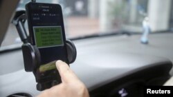 Một tài xế GrabTaxi dùng điện thoại để kiểm tra hóa đơn cho một khách hàng ở Hà Nội, Việt Nam, ngày 9/9/2015.