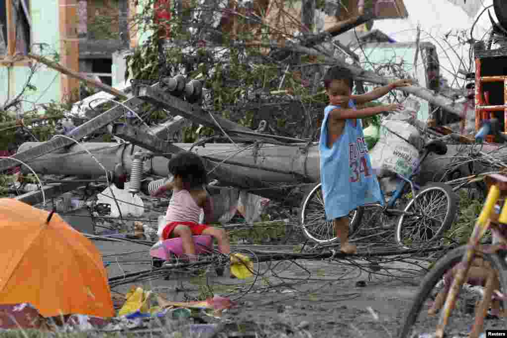 Trẻ em chơi gần cột điện bị hư hại sau Siêu bão Haiyan tại thành phố Tacloban, miền trung Philippines, ngày 9/11/2013.