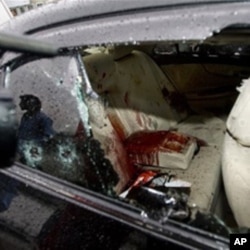 A Pakistani cameraman films the blood-stained damaged car of slain Pakistan's government minister for religious minorities Shahbaz Bhatti outside the emergency ward of a local hospital in Islamabad, Pakistan on Wednesday, March 2, 2011. Gunmen shot and ki