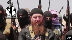 FILE - Omar al-Shishani standing next to Islamic State of Iraq and the Levant (ISIL) spokesman among a group of fighters as they declare elimination of border between Iraq and Syria.