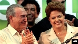 Brazil's President-elect Dilma Rousseff, right, smiles as Vice President-elect Michel Temer applauds upon her arrival to give her victory speech after winning the election runoff in Brasilia, Brazil, 31 Oct. 2010.