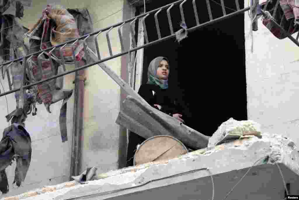 A girl stands on her balcony to check the damage in her neighborhood in Aleppo's district of al-Shaar, Syria, September 16, 2012. 