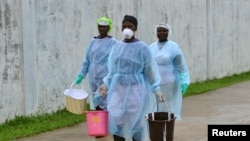 Nhân viên y tế xách các thùng nước khử trùng tại trung tâm điều trị Ebola ở Monrovia, Liberia, ngày 25/9/2014.