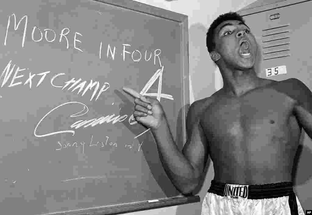 Vận động viên quyền anh trẻ tuổi Cassius Clay, sau này đổi tên thành Muhammad Ali, chỉ vào tấm bảng trong phòng thay đồ mà anh dùng phấn viết lên đó trước trận so găng với Archie Moore ở Los Angeles ngày 15/11/1962.