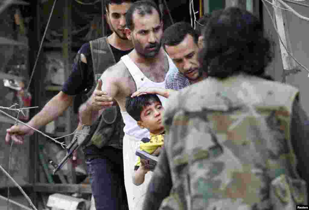 Residents and members of the Free Syrian Army help a boy who was wounded by a jet shelling in al-Shaar, Aleppo, Syria, September 16, 2012.