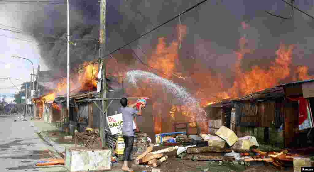 Một người đàn ông dội nước vào ngôi nhà đang bốc cháy ở Zamboanga, Philippines, ngày 12/9/2013.